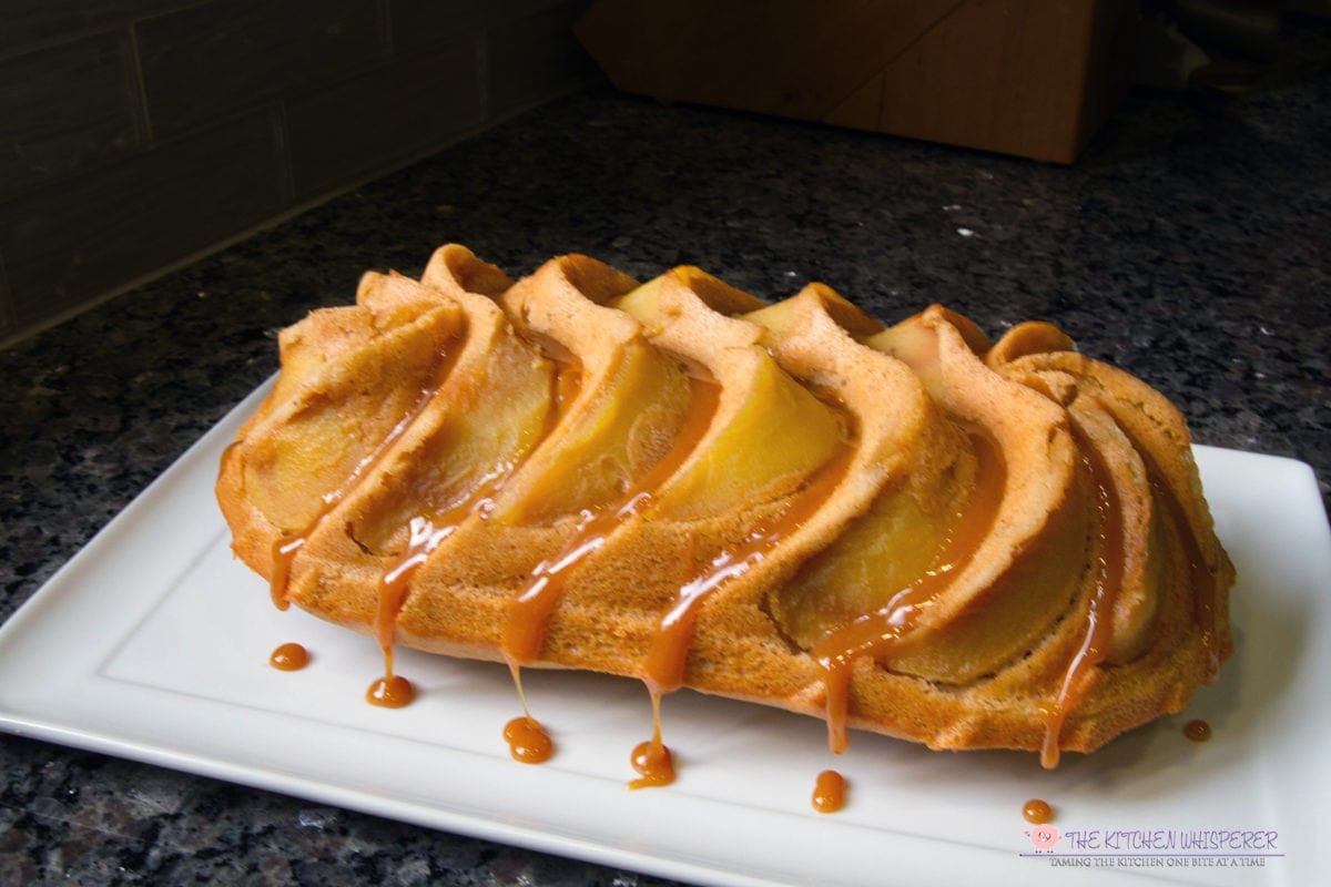 Swirls of apples nestled in a tender vanilla bean flecked cake drizzled in a luscious caramel and a kiss of confectioners' sugar. This cake is simply delicious in the most beautiful of ways. #bundt #cake #applecake #caramel #thekitchenwhisperer #nordicware