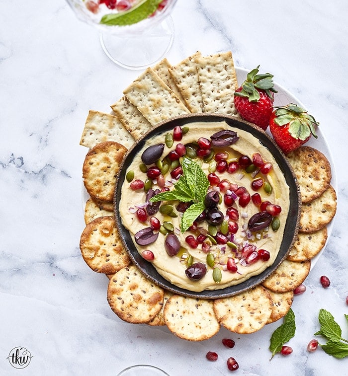 This Mediterranean Hummus Bowl is garnished with kalamata olives, toasted pepitas, arils, red onions, and a kiss of mint for a tasty vegetarian snack or lunch!