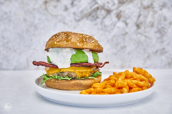 Say hello to your new favorite burger! Ground bacon & seasonings are mixed with ground chicken to make this the ultimate grilled burger! Top with melted cheese, arugula, crispy bacon, and parmesan ranch for absolute deliciousness! Ultimate Ground Chicken Bacon Ranch Burger, crack chicken burger, ground bacon burger, ranch chicken burgers, ultimate chicken burger, best chicken burger