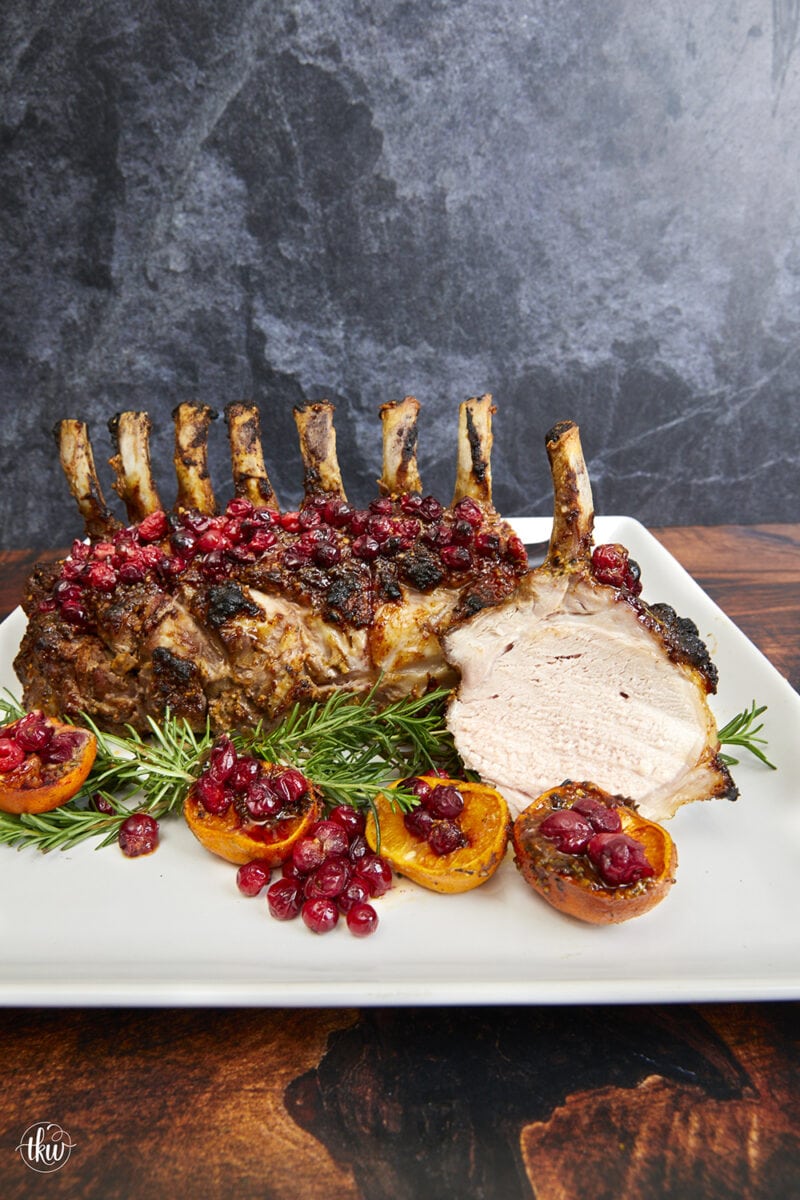 Make your holidays more spectacular with this mustard-glazed spiced rack of pork with cranberries, orange, and fresh rosemary slow-roasted to perfection. Ultimate Roasted Orange Cranberry Rosemary Rack of Pork, holiday pork, christmas dinner, roasted pork, roasted rack of pork, crown of pork