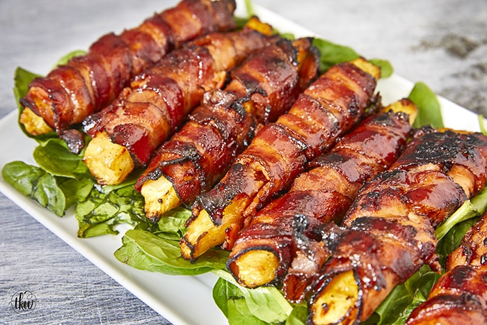 Get ready for a mouthwatering culinary adventure with a sweet and savory twist. Imagine crispy bacon, candied ham, juicy pineapple that's baked to perfection and finished with a decadent buttery maple bourbon glaze!Ultimate Buttery Maple Bourbon Glazed Candied Bacon Pineapple Spears, bacon wrapped pineapple, yoder smokers pizza oven, maple bourbon butter sauce, candied ham, summer cookout recipes, cookout appetizers, grilled pineapple