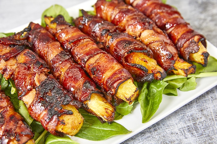 Get ready for a mouthwatering culinary adventure with a sweet and savory twist. Imagine crispy bacon, candied ham, juicy pineapple that's baked to perfection and finished with a decadent buttery maple bourbon glaze!Ultimate Buttery Maple Bourbon Glazed Candied Bacon Pineapple Spears, bacon wrapped pineapple, yoder smokers pizza oven, maple bourbon butter sauce, candied ham, summer cookout recipes, cookout appetizers, grilled pineapple