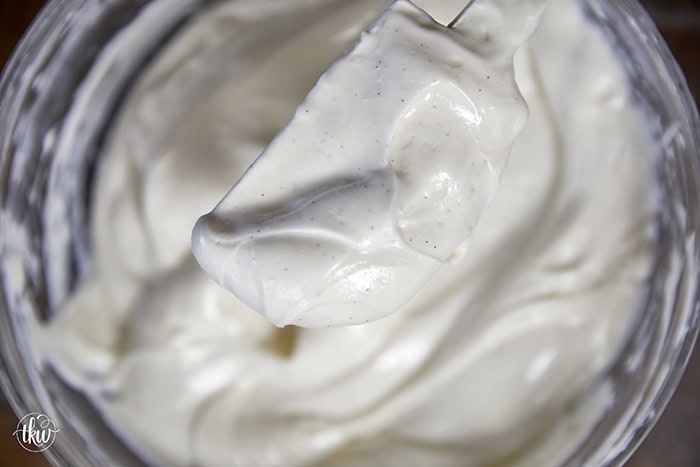 Whisking a light and airy Italian ricotta cheesecake filling with visible vanilla bean specks in a glass mixing bowl.