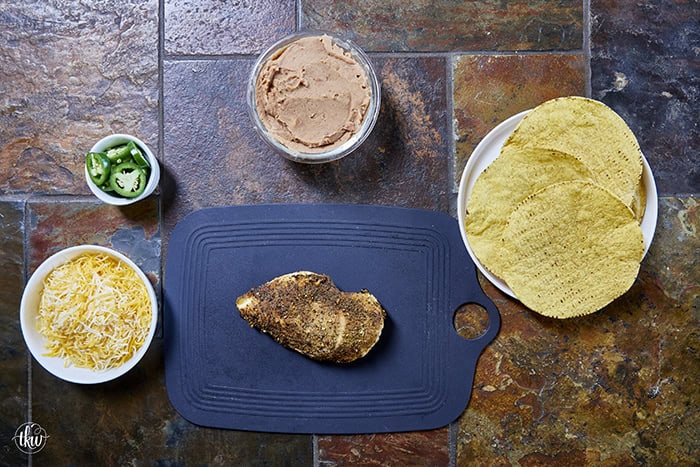 The crunch you've been craving! These Loaded Chicken and Bean Tostadas feature golden-baked shells, seasoned refried beans, juicy chicken, bubbly Mexican cheese, and spicy jalapeños. Finished with a cool sour cream sauce and fresh cilantro for that perfect creamy-meets-crunchy bite. If you love tacos, you have to try this 30-minute twist! #ChickenTostadas #30MinuteMeals #EasyMexicanRecipes #WeeknightDinnerIdeas #BudgetFriendlyCooking