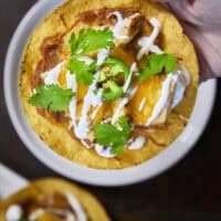 The crunch you've been craving! These Loaded Chicken and Bean Tostadas feature golden-baked shells, seasoned refried beans, juicy chicken, bubbly Mexican cheese, and spicy jalape&ntilde;os. Finished with a cool sour cream sauce and fresh cilantro for that perfect creamy-meets-crunchy bite. If you love tacos, you have to try this 30-minute twist! #ChickenTostadas #30MinuteMeals #EasyMexicanRecipes #WeeknightDinnerIdeas #BudgetFriendlyCooking