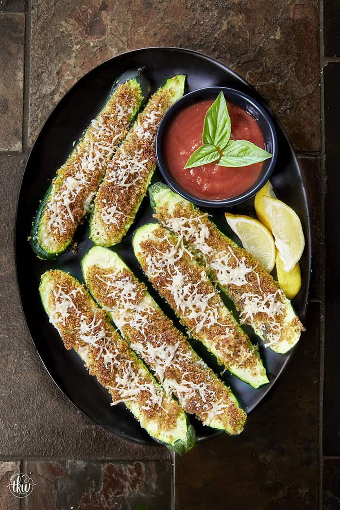 These easy zucchini strips are topped with a toasted Parmesan herb crust! Made in the oven or air fryer, they are the perfect light summer side dish or appetizer to pair with your favorite dipping sauce. #easyzucchini #zucchinistrips #bakedzucchini