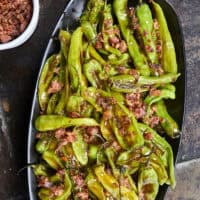 Blistered to perfection and tossed in a sticky, homemade garlic-honey glaze, these shishito peppers hit every single craving. Top them with crispy bacon crumbles for a 15-minute, sweet-and-smoky umami bomb. #ShishitoPeppers #honeygarlicsauce #fingerfoods