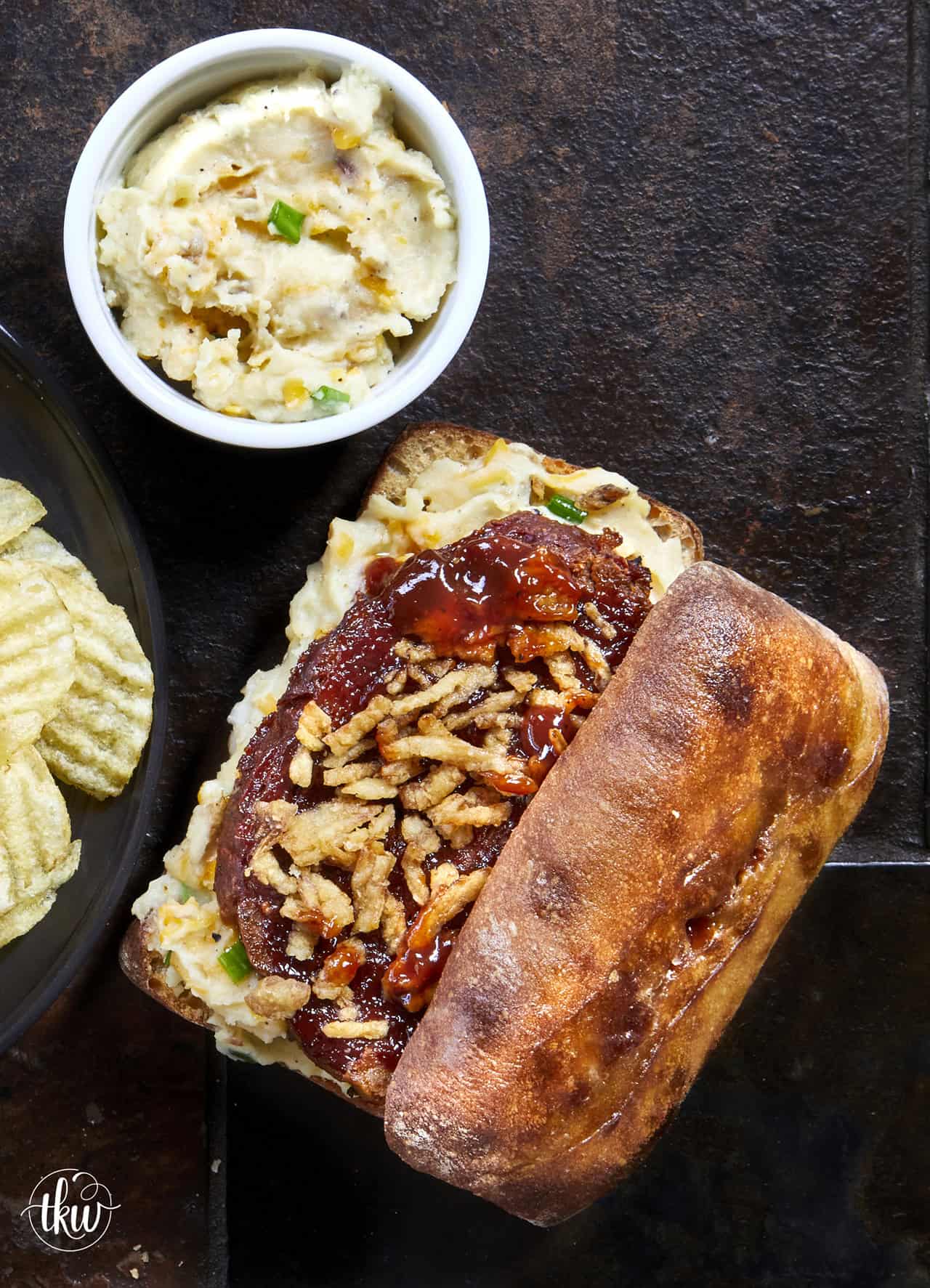 Hot Sheet Pan BBQ Meatloaf and Cheddar Mashed Potato Sandwich served on toasted ciabatta with crispy onion straws and sticky glaze.