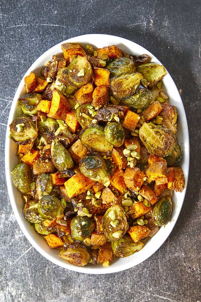 Sheet-pan roasted Brussels sprouts and sweet potatoes tossed in a warm spiced maple glaze and toasted pistachios. An easy side dish that is naturally vegan, gluten-free, and perfect for any dinner table.